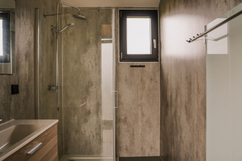 Baño moderno con ducha, lavabo y ventana pequeña en una tiny house del Holiday park Eigen Wijze, Países Bajos.