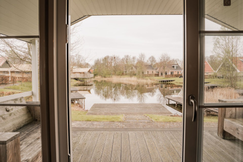 Vista desde una cabaña grupal en Holiday park Eigen Wijze en Países Bajos, con lago y casas rurales.