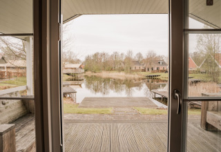 Uitzicht vanuit een groepslodge bij Holiday park Eigen Wijze in Nederland met een meer en vakantiehuisjes.