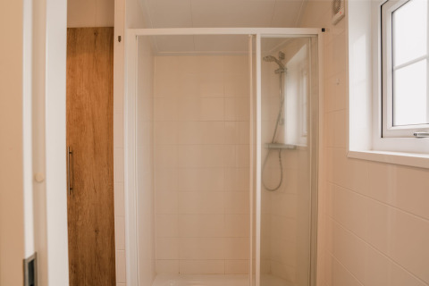 Douche moderne avec porte en verre et porte en bois au Group lodge du Holiday park Eigen Wijze, Pays-Bas.