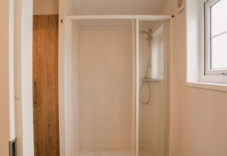 Moderne Dusche mit Glastür und Holztür im Group Lodge im Holiday Park Eigen Wijze, Niederlande.