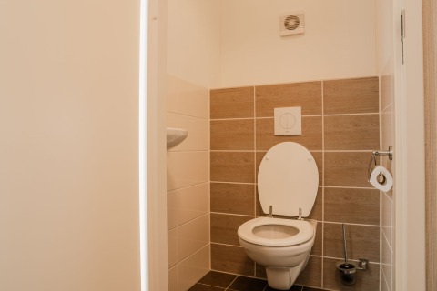 Modern toilet met wandcloset en beige tegels in Group lodge op Holiday park Eigen Wijze in Nederland.