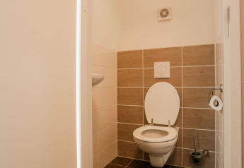 Toilettes modernes avec WC suspendus et carrelage beige au Group lodge du Holiday park Eigen Wijze aux Pays-Bas.