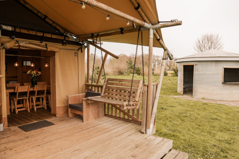 Tente safari glamping avec terrasse en bois, balançoire et hutte ronde au Holiday park Eigen Wijze aux Pays-Bas.