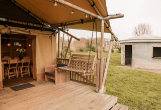 Tienda glamping tipo safari con terraza de madera y columpio en Holiday park Eigen Wijze, Países Bajos.