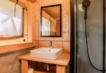Badkamer in een glampingtent bij Holiday park Eigen Wijze in Nederland met wastafel en spiegel.