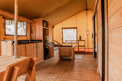 Interieur van een glamping safaritent bij Holiday park Eigen Wijze in Nederland met houten inrichting.