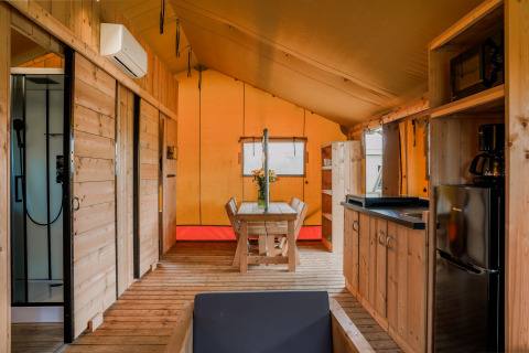 Binnenkant van een safari glamping tent in Holiday park Eigen Wijze met houten meubels in Nederland.