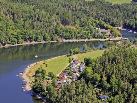 Vista aérea del parque vacacional BoerenBed Hohenwarter Seehof junto a un río, rodeado de bosque en Turingia, Alemania.