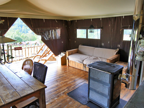 Intérieur de tente glamping au BoerenBed Hohenwarter Seehof en Thuringe, Allemagne, avec poêle, canapé et table.