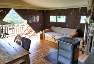 Gezellige glampingtent bij BoerenBed Hohenwarter Seehof in Thüringen, Duitsland met houtkachel en bank.
