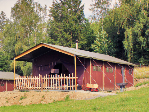 Gemütliche Holzhütte mit Veranda im Grünen, aufgenommen im BoerenBed Hohenwarter Seehof in Thüringen.
