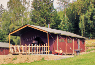 Lodge en bois avec véranda couverte dans une forêt au BoerenBed Hohenwarter Seehof en Thuringe, Allemagne.