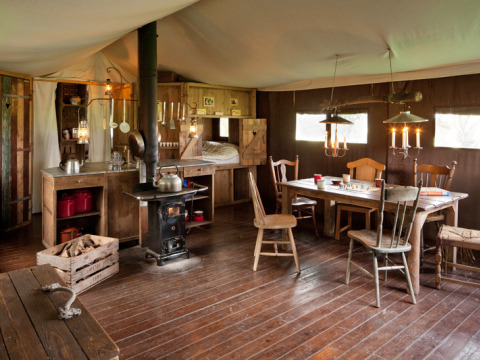 Gemütliche Holzhütte mit Küche, Holzofen, Esstisch und Stühlen im BoerenBed Hohenwarter Seehof, Thüringen.