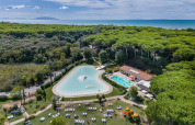 Luchtfoto van Sandaya Etruria vakantiepark in Toscane, Italië, met zwembaden, bos en zee op de achtergrond.