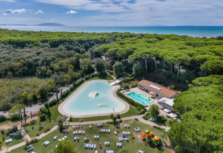 Aerial view of Sandaya Etruria holiday park in Tuscany, Italy, showing pools, forest and sea in the background.
