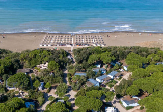Vista aérea del parque vacacional Sandaya Etruria en la Toscana, Italia, con árboles, cabañas y playa.