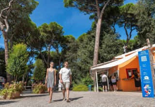 Coppia passeggia al parco vacanze Sandaya Etruria tra alberi e sole in Toscana, Italia.