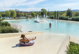 Bambino scivola su ciambella gonfiabile nel parco acquatico Sandaya Etruria in Toscana, Italia.