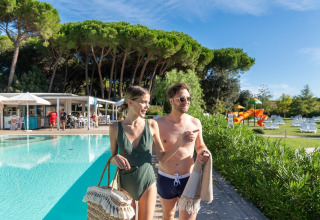 Jong koppel wandelt bij het zwembad in het Sandaya Etruria vakantiepark in Toscane, Italië op een zonnige dag.