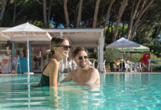 Un jeune couple profite de la piscine au Sandaya Etruria, un parc de vacances ensoleillé en Toscane, Italie.