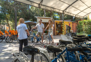 Gäste im Sandaya Etruria Ferienpark in der Toskana erhalten Fahrradinstruktionen unter einem Unterstand.