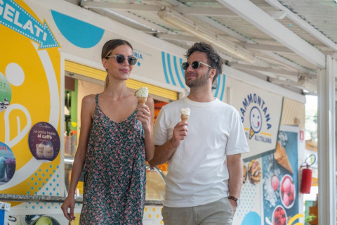 Una giovane coppia gusta un gelato davanti a una gelateria al Sandaya Etruria holiday park in Toscana, Italia.