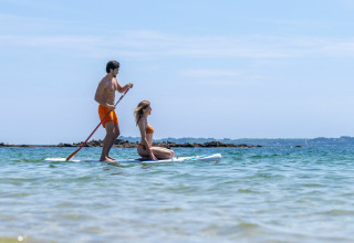 Koppel geniet van stand up paddleboarden op zee bij Sandaya Etruria vakantiepark in Toscane, Italië.