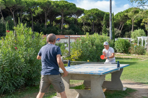Twee personen spelen buiten pingpong bij vakantiepark Sandaya Etruria in Toscane, Italië, tussen het groen.