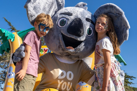 Deux enfants maquillés posent avec une mascotte koala au Sandaya Etruria, un parc de vacances en Toscane.