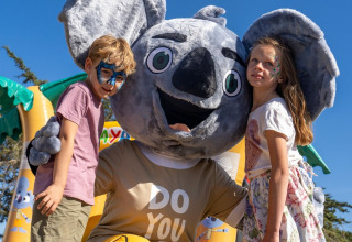 Deux enfants maquillés posent avec une mascotte koala au Sandaya Etruria, un parc de vacances en Toscane.
