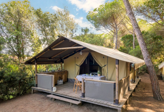 Safari-teltet Tent Kenya med træveranda og udendørs spisebord i en fredelig skovomgivelse.