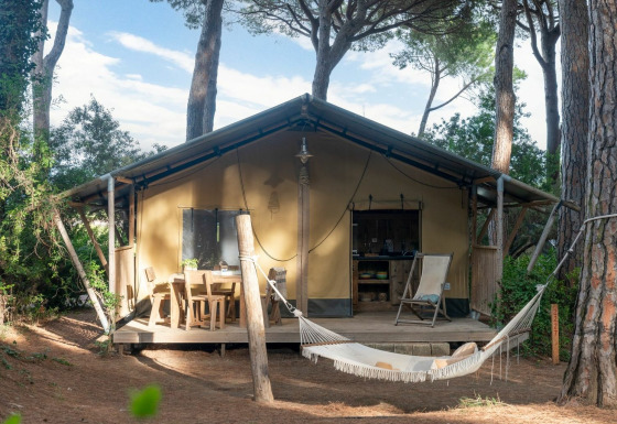 Safari tent Country Lodge met houten terras, hangmat en zitruimte tussen bomen in een bosrijke omgeving.