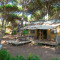 Safari tent Lodge Oasi met houten veranda, hangmat en zitgedeelte tussen hoge bomen in het bos.