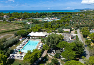 Aerial view of Sandaya Toscana Bella holiday park in Tuscany, Italy, featuring a pool, trees, and sea view.