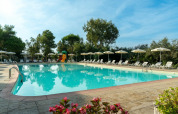 Piscine extérieure avec transats et parasols au Sandaya Toscana Bella, parc de vacances en Toscane, Italie.