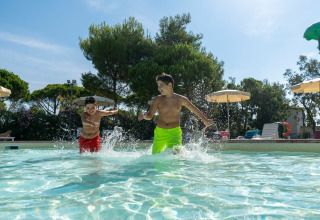 Twee jongens spelen en spetteren in het zwembad bij Sandaya Toscana Bella, een vakantiepark in Toscane, Italië.