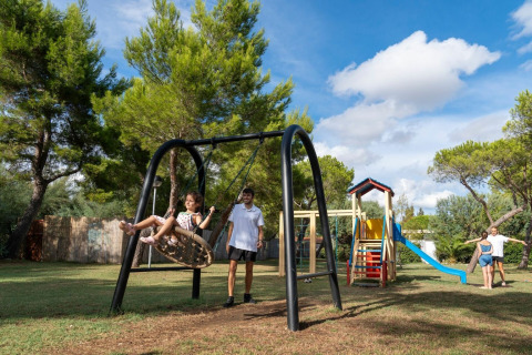 Children play on swings and a slide at the playground in Sandaya Toscana Bella holiday park in Tuscany, Italy.