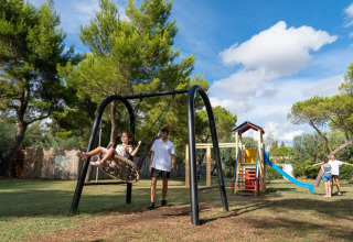 Children play on swings and a slide at the playground in Sandaya Toscana Bella holiday park in Tuscany, Italy.