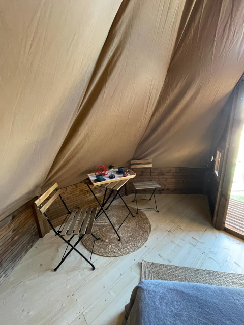 Interieur van een Tipi Junior tent bij Weekend Glamping Resort in Italië met tafeltje, stoelen en kleed.