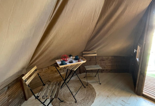 Interieur van een Tipi Junior tent bij Weekend Glamping Resort in Italië met tafeltje, stoelen en kleed.