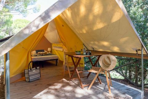Safaritent Tent Aventure bij Sandaya Etruria in Italië met bed, tafel, stoelen en strohoed op terras.
