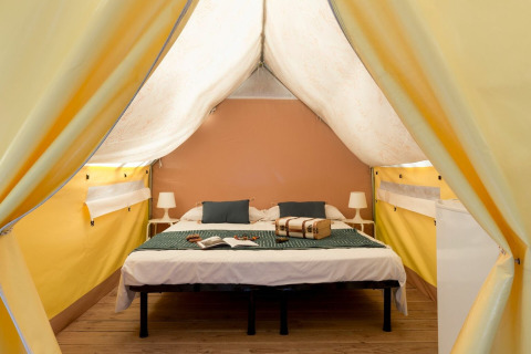 Interior de tienda safari en Tent Aventure, Sandaya Etruria, Italia, con cama doble y decoración moderna.