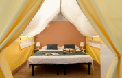 Interior de tienda safari en Tent Aventure, Sandaya Etruria, Italia, con cama doble y decoración moderna.
