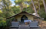 Tienda safari Tent Kenya en Sandaya Etruria, Italia, rodeada de pinos altos y vegetación natural.