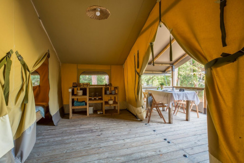 Interior de una tienda safari con suelo de madera y zona de comedor en Tent Kenya, Sandaya Etruria, Italia.