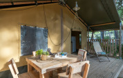 Zona de comedor al aire libre en la tienda safari Country Lodge de Sandaya Etruria, Italia, con muebles de madera.