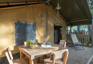Udendørs spiseområde ved safari-teltet Country Lodge på Sandaya Etruria, Italien, omgivet af natur.
