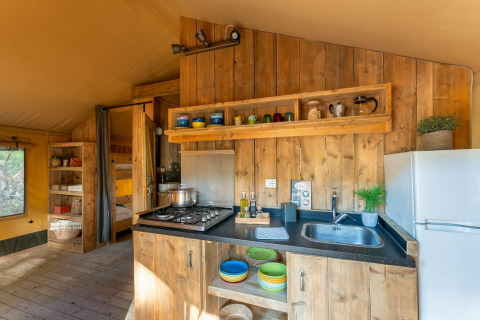 Keukengedeelte in een safaritent van Country Lodge bij Sandaya Etruria in Italië, met hout en kleurrijk servies.