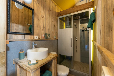 Badeværelse i Country Lodge safari telt på Sandaya Etruria, Italien, med trævægge og moderne bruser.